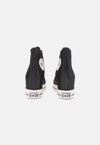 Zwarte high-top sneakers van denim met een witte rubberen zool. Voorzien van een cirkelvormige logo patch en metalen oogjes aan de zijkanten.
