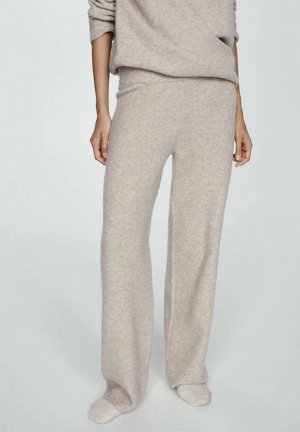 Pantalon en maille beige doux avec une coupe décontractée, porté avec des chaussettes assorties en maille et un pull ample coordonné.