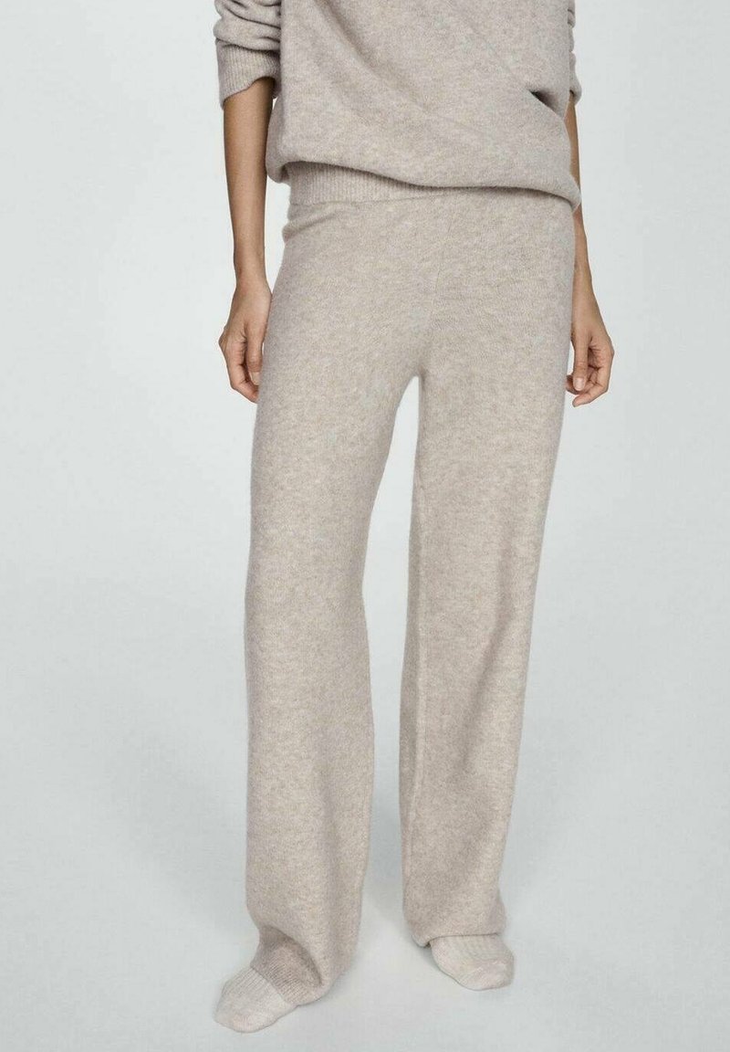 Pantalon en maille beige doux avec une coupe décontractée, porté avec des chaussettes assorties en maille et un pull ample coordonné.