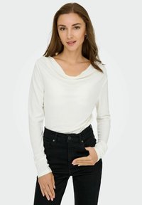 Witte longsleeve top met een colontwerp, gecombineerd met hoge zwarte jeans. Zachte stof, aansluitende mouwen, minimale details.
