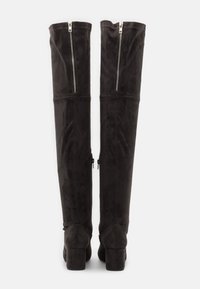 Stivali neri in suede alti fino al ginocchio con tacco a blocco, dotati di cerniere sul retro e una texture liscia e opaca.