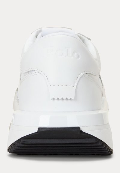 Balta sportinė avalynė matoma iš kulno pusės, su juodu tekstūruotu pado paviršiumi ir subtiliu įspaustu "Polo" ženklu gale.