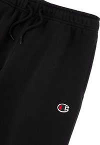 Zwarte katoen joggers met een verstelbare koordsluiting in de taille en een klein geborduurd logo op het linkerbeen. Glad oppervlak overal.