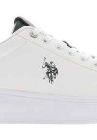 Valkoiset lenkkarit, joissa on sileä nahkapinta, pyöreät nauhat, hopeiset silmukat ja musta-valkoinen polo-grafiikka sivussa.