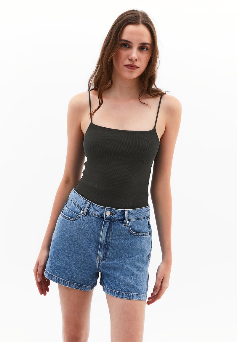 Donkergroen geribbelde tanktop met dunne bandjes, gecombineerd met lichtblauwe denimshorts met een hoge taille en opgerolde zoom.