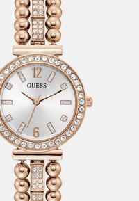 Zegarek w różowym złocie z okrągłą srebrną tarczą, kryształowymi akcentami wokół ramki oraz bransoletką z koralików z wbudowanym kryształem.