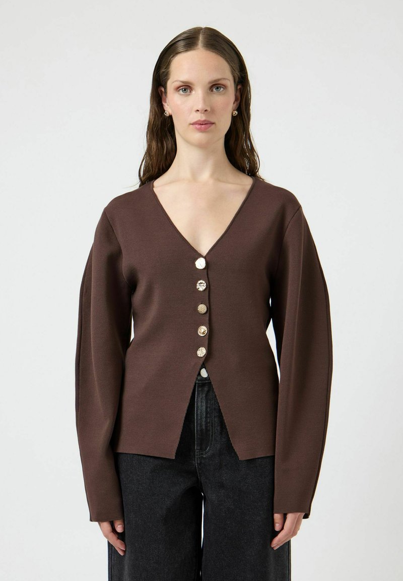 Brązowy kardigan z dzianiny z dekoltem w serek, z sześcioma dekoracyjnymi guzikami z przodu. Długie rękawy i rozcięcie u dołu.