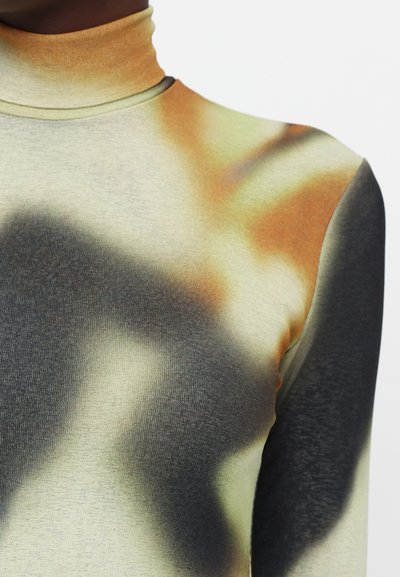 Top z dolgimi rokavi in turtleneck iz lahkega blaga, ki ima abstraktni vzorec v odtenkih bež, črne in oranžne. Gladka tekstura.