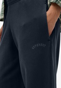 Donkergrijze joggingbroek van een katoenmix, met een gestructureerde afwerking, elastische tailleband, zijzakken en het 'Superdry' logo in subtiele stiksel.