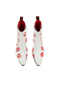 Botas blancas hasta el tobillo con patrones de labios rojos, diseño de punta afilada, acentos negros y forro interior rojo. Presentan cremalleras a ambos lados.