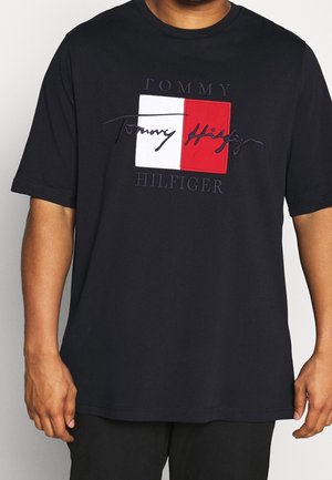 Mørk marineblå bomuld t-shirt med en rød og hvid logo-patch med broderet tekst. Korte ærmer, afslappet pasform og rund hals.