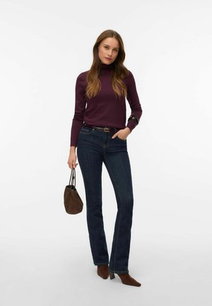 Bordowy golf, ciemnoniebieskie dzwony, brązowe botki na obcasie oraz mała brązowa torebka. Gładkie tekstury z dopasowanym krojem.