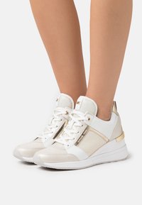 Białe i złote sneakersy z teksturowanej tkaniny i gładkiej skóry. Wyposażone w metaliczne akcenty, sznurówki z przodu i wyściełaną podeszwę.
