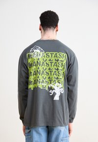 Long-sleeve gray t-shirt featuring green dripping text and a white cartoon character on the back. Cotton material with relaxed fit.