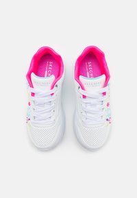 Bílé tenisky Skechers s růžovým interiérem a tkaničkami, které mají texturovaný design s barevnými květinovými vzory po stranách.