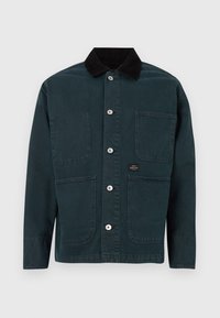 Chaqueta verde oscura con cuello de pana, dos bolsillos frontales y cinco botones de metal para el cierre. Diseño simple con líneas limpias.