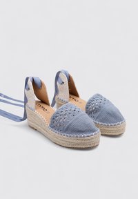 Espadrilles tejidas en azul con una puntera texturizada, suela de yute en cuña y cintas de raso de color azul claro que contrastan. Diseño de apertura en la parte trasera con tejido transpirable.