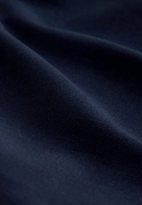 Tissu bleu marine à texture lisse, présentant un fin nervurage et des plis doux, mettant en valeur ses caractéristiques de douceur et de légèreté.