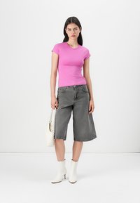 Tilpasset rosa kortermet t-skjorte, grå vide denimshorts, hvite ankelstøvler og en liten hvit håndveske. Minimalistisk design, glatt tekstur.