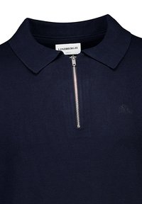 Tummansininen puuvillapaita, jossa on vetoketjullinen kaulus, ribbikuvio ja hillitty brodeerattu logo rinnassa. Slim fit -malli.