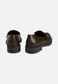 Donkerbruine leren schoenen met een gladde afwerking, een laag profiel en een platte rubberen zool. Beschikt over een subtiele vormgeving en achterlussen voor eenvoudig aan- en uittrekken.