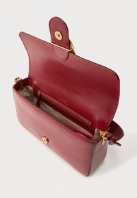 Ορθογώνια, δομημένη τσάντα χειρός από βαθιά βουργουνδί δέρμα με υφή. Διαθέτει επίχρυσα μεταλλικά στοιχεία, κλείσιμο με μαγνητικό καπάκι και εσωτερική τσέπη με φερμουάρ.