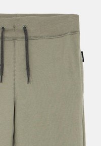 Vaaleanvihreät puuvillaiset collegehousut, joissa on resorivyötärö, nyöri ja sivusauman yksityiskohtia. Sivussa pieni merkkilappu.