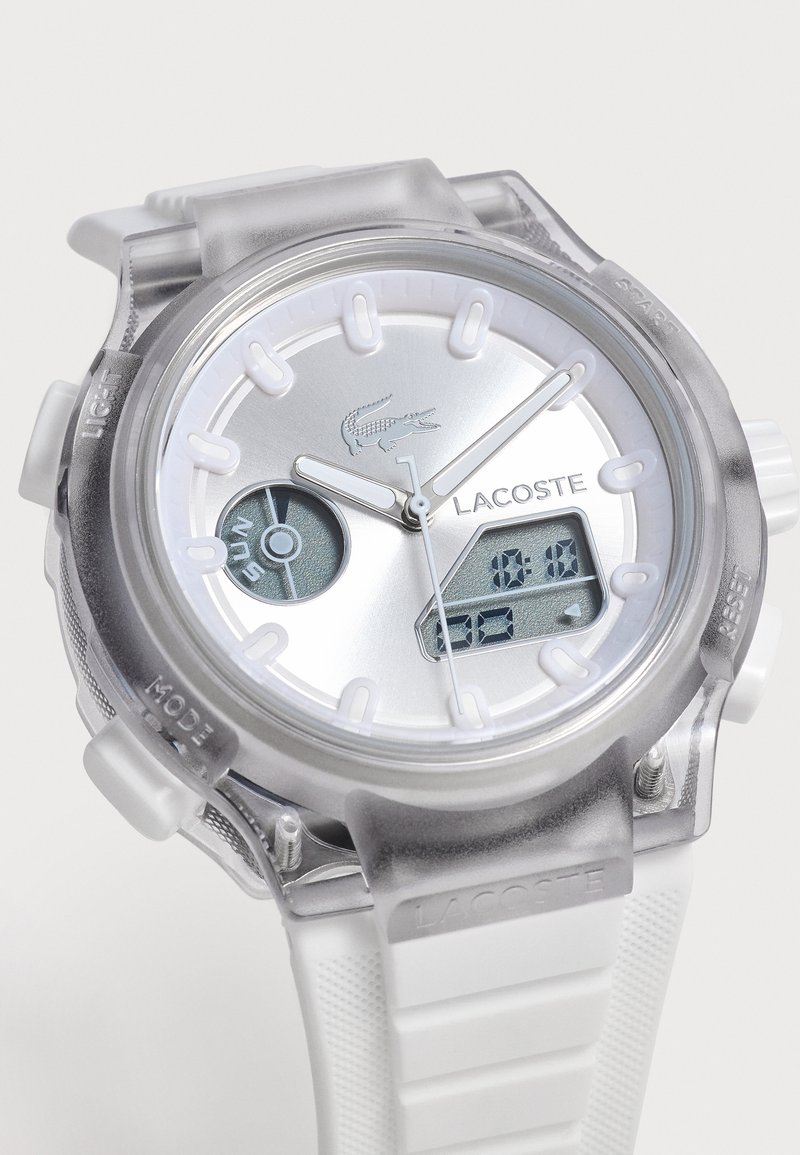 Orologio da polso Lacoste argento con lancette analogiche, display digitali per giorno e data, cassa traslucida e cinturino in gomma bianca strutturata.