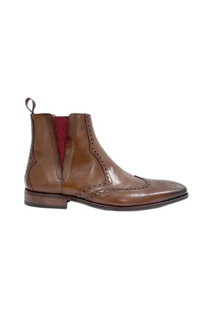 Botín Chelsea de cuero marrón con perforaciones tipo brogue, paneles laterales de elastano rojos y una lengüeta, sobre un fondo blanco.
