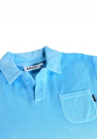 Lyseblå polo med blød tekstur, krave og lille brystlomme med sort logoetiket. Glat stoffinish.