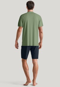 Groene t-shirt met korte mouwen en een ronde hals, gecombineerd met marineblauwe shorts. De stof is glad en heeft een relaxte pasvorm.