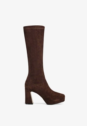 Stivale in suede marrone fino al ginocchio con un tacco spesso e squadrato e suola piatta; presenta dettagli di cucitura minimal e una texture liscia.