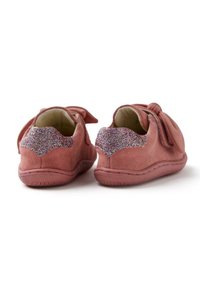 Des chaussures en daim rose avec des accents scintillants texturés sur le talon et un détail en nœud sur la languette. Semelle flexible avec des coutures le long du bord.