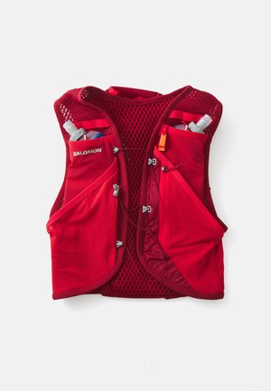Czerwona kamizelka biegowa wykonana z lekkiego, oddychającego materiału. Posiada siateczkowe panele, dwie boczne kieszenie na butelki z wodą oraz regulowane ramiączka.