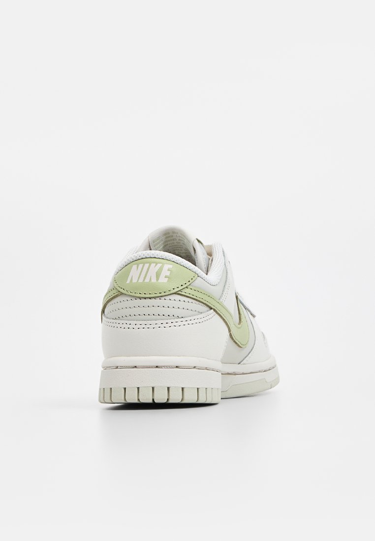 Baskets Nike avec un dessus en cuir blanc et des accents vert clair. Elles présentent un col rembourré, une pointe arrondie et une semelle en caoutchouc texturée.