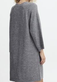 Robe tricotée grise à coupe décontractée, avec manches longues, encolure ronde et fentes latérales pour faciliter les mouvements. Texture douce.