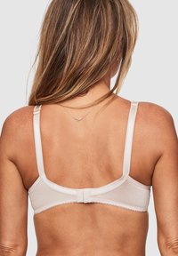 Beige bralette van gladde stof, met verstelbare banden en een eenvoudige haaksluiting. Heeft een scalloped rand langs de randen.