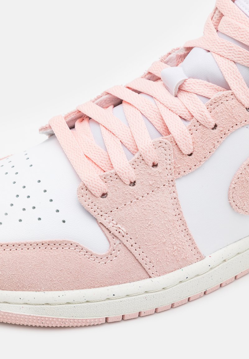 Basket en daim rose et cuir blanc avec des accents texturés, un boîte à orteils perforée et des lacets roses. Semelle épaisse blanche avec des éclats.