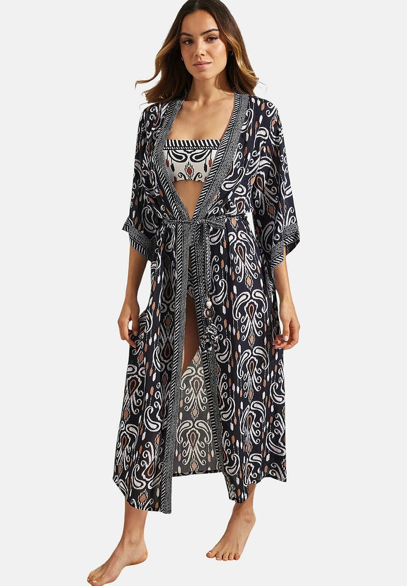 Zwarte doorzichtige kimono met witte en oranje bloempatronen, open voorkant, wijde mouwen en een strik taille. Bevat een bijpassende bandeau met patroon eronder.