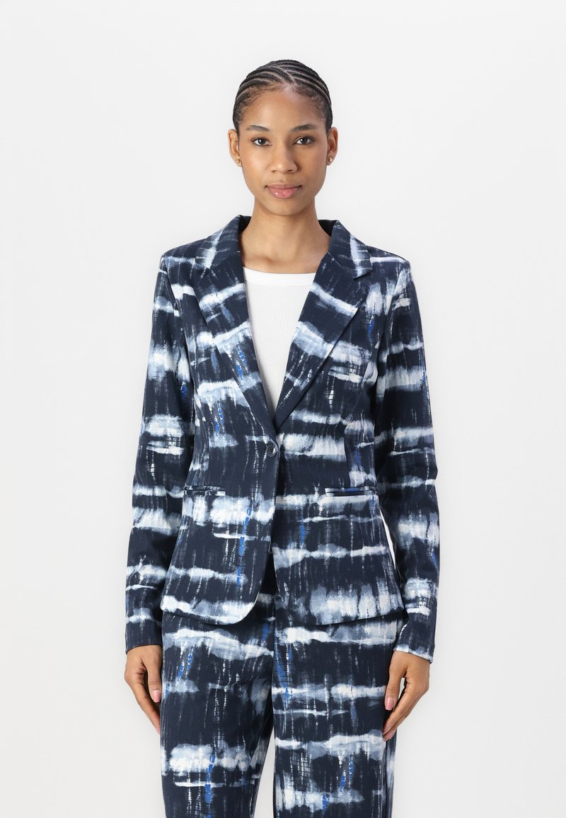Námornícke sako s tie-dye vzorem v bílé a modré barvě, s jednobodovým zapínáním a dvěma předními kapsami, vyrobené z hladkého materiálu.