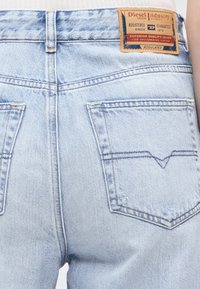 Φωτεινό γαλάζιο τζιν ντένιμ από πίσω, που δείχνει δύο τσέπες και μια καφέ δερμάτινη ετικέτα της Diesel Industry στη μέση.