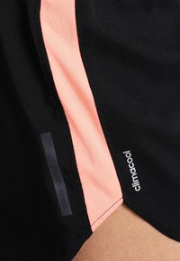Czarne krótkie spodenki biegowe z różowym siateczkowym panelem bocznym, z etykietami "adidas running" i "climacool", gładka tekstura.