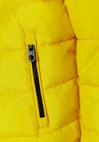 Tissu de veste en duvet jaune avec un motif matelassé. Comprend une poche zippée noire avec un tirette ronde et une couture contrastante.