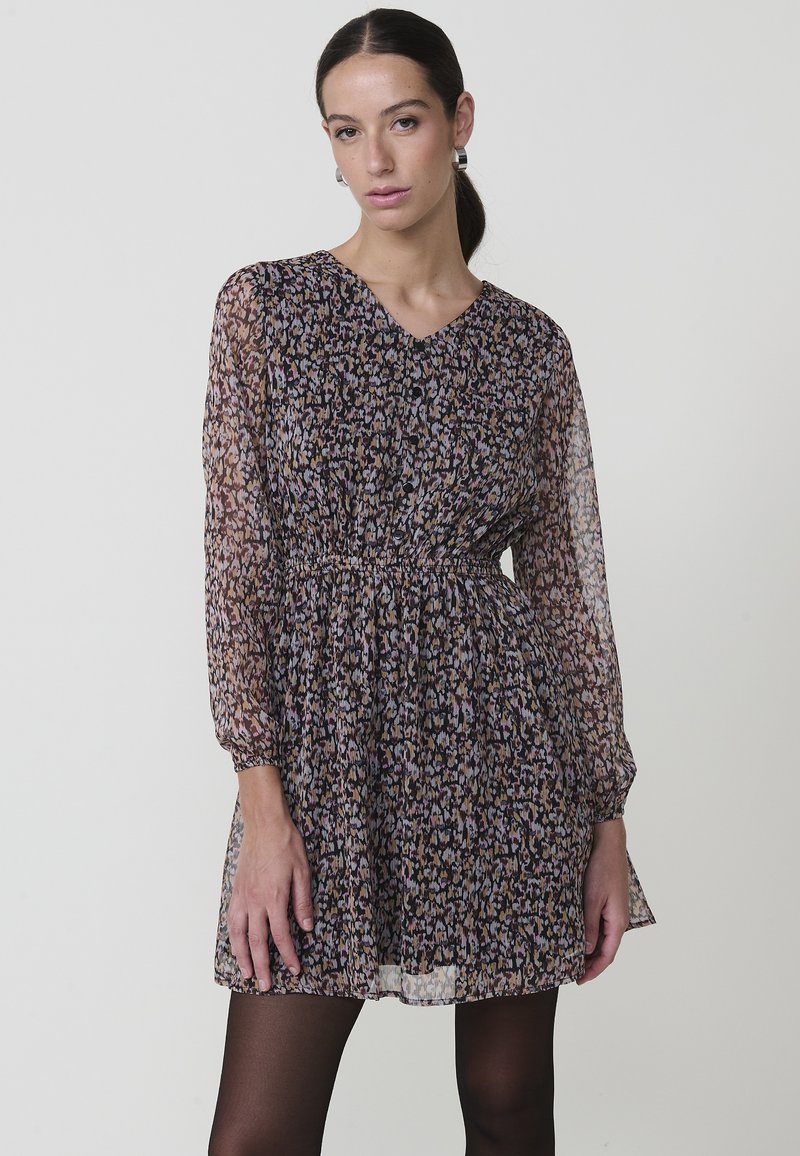 Vestido de manga larga en tela transparente y estampada, con escote en V, cintura gather, y un diseño floral en tonos de púrpura, rosa y negro.