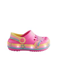 Rosa Clog-Schuh mit einem regenbogenfarbenen Riemen, Sterndekorationen und leuchtender Sohle vor einem weißen Hintergrund.