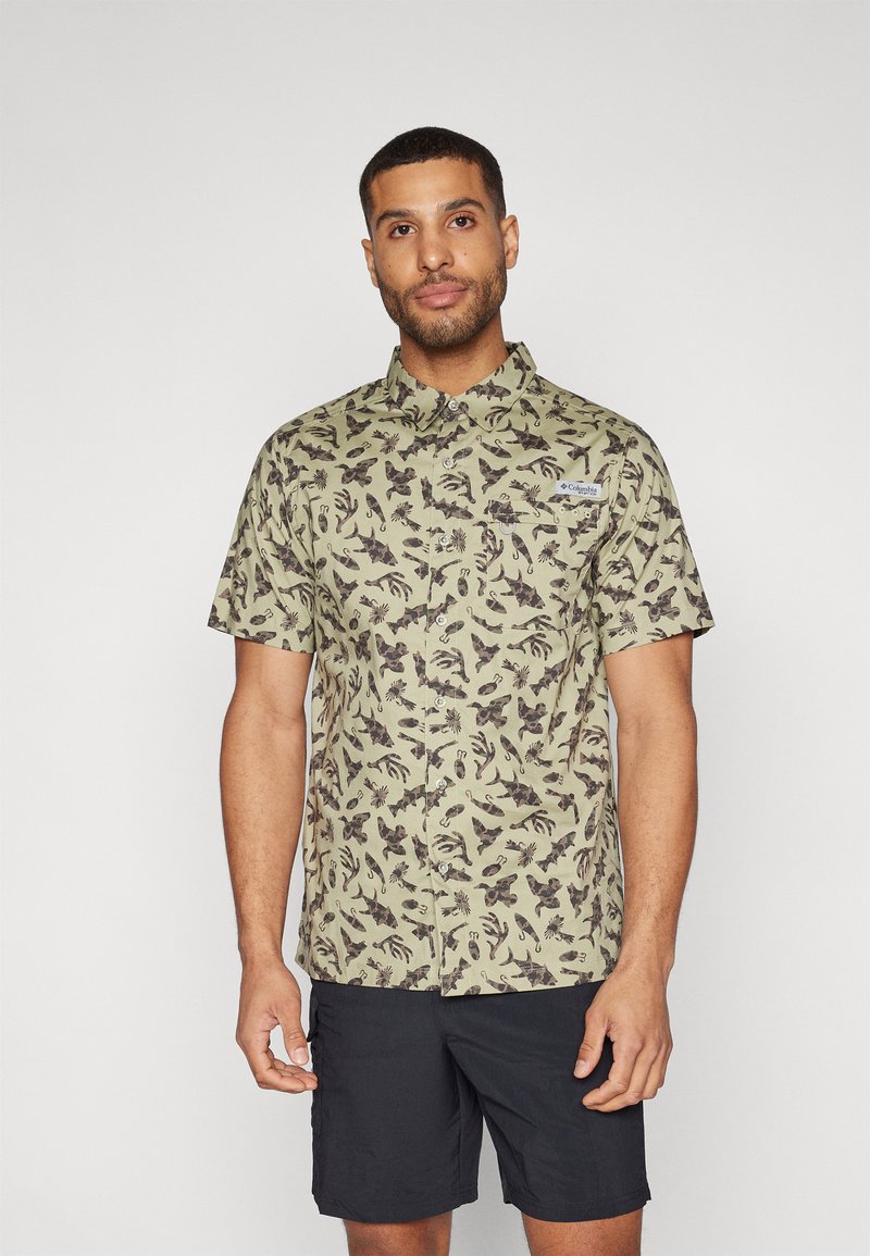 Korte mouw, licht olijfgroen shirt met een bruine botanische print, voorzien van een button-down kraag en een zak op de linker borst. Gekocht met donker gekleurde shorts.