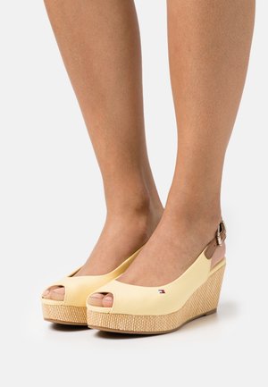 Sandales compensées jaunes à bouts ouverts, plateforme en jute texturée, et bride de cheville marron réglable. Logo Tommy Hilfiger affiché sur le côté.