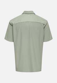 Camisa de manga corta con cuello en verde claro, con una tela texturizada con rayas verticales y un corte recto en el dobladillo y los hombros.
