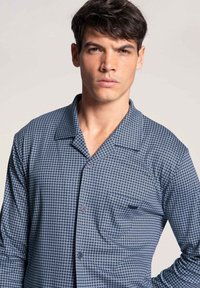 Blauw shirt met patroon, korte revers, voorkant met zak en knopen. Kenmerkt zich door een geometrisch print en een gladde textuur.