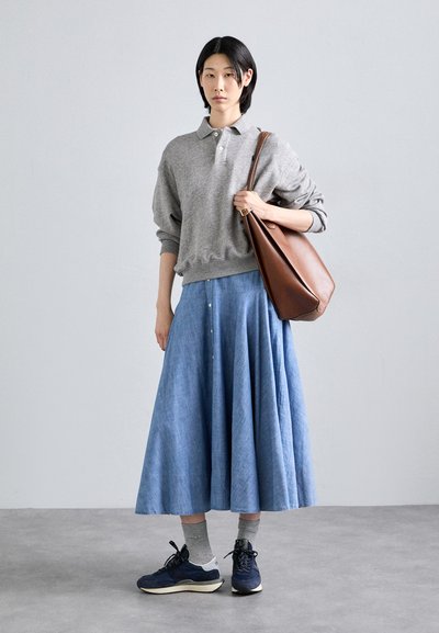 Gray sweatshirt with a collar, blue pleated skirt, gray socks, navy sneakers, and a brown leather shoulder bag. Textured fabrics and relaxed fit.